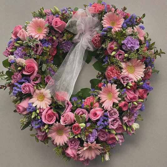 Heart-shaped spring wreath with pink roses and purple blooms, a funeral tribute for love and remembrance. Best in Toronto.