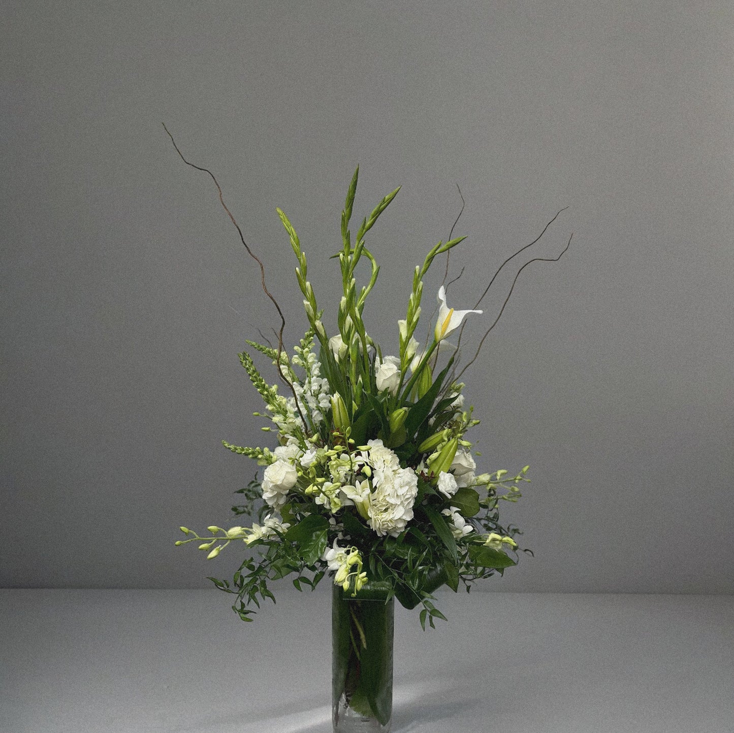 Elegant sympathy flower arrangement with white roses, lilies, and greenery, designed to express love and remembrance