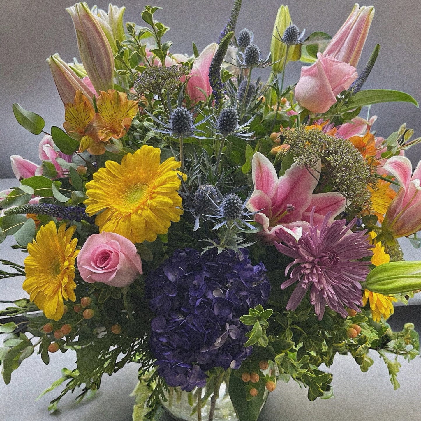 Chic and modern floral centerpiece with delicate orchids, roses, and pampas grass – perfect for sophisticated home or event decor