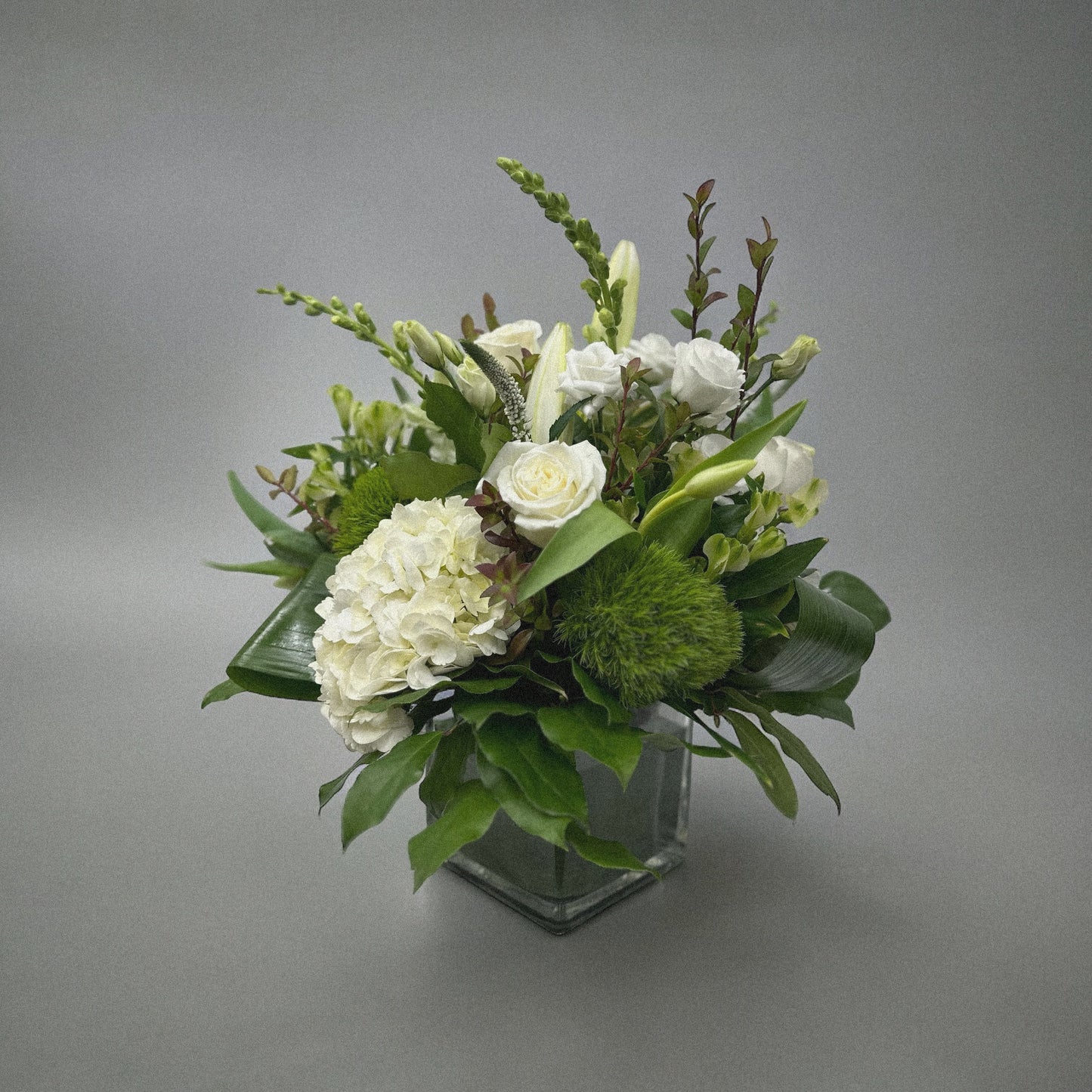 Luxury white floral arrangement with hydrangeas, roses, and lilies in a glass vase. Perfect for any occasion, best florist in Toronto.