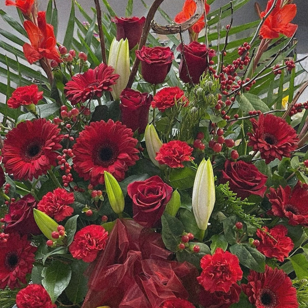 Luxury red funeral arrangement with roses, gerberas, and lilies. Best in Toronto for sympathy, same-day delivery available.