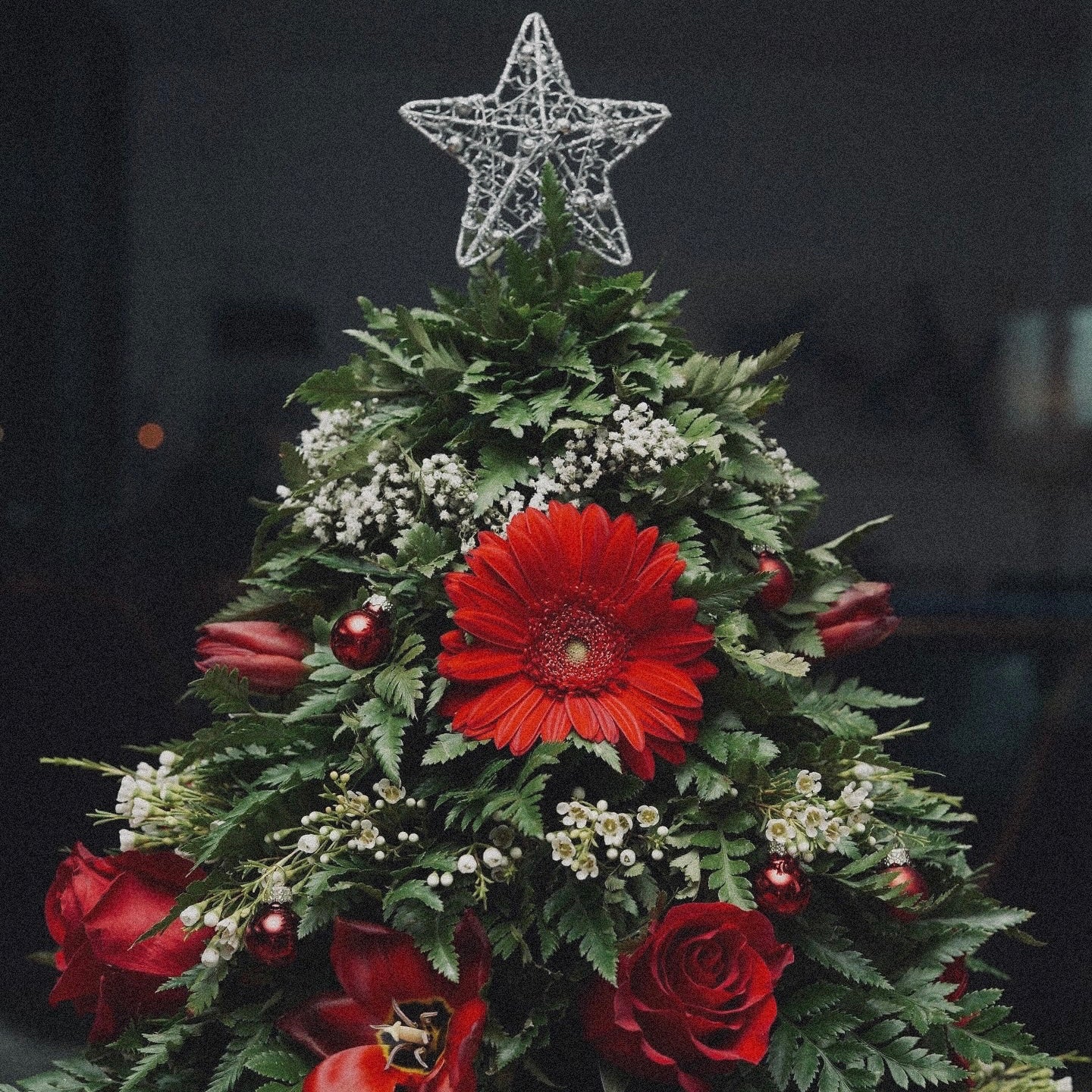 Winter-themed floral centerpiece with white roses, pinecones, and festive greenery, perfect for holiday decor.
