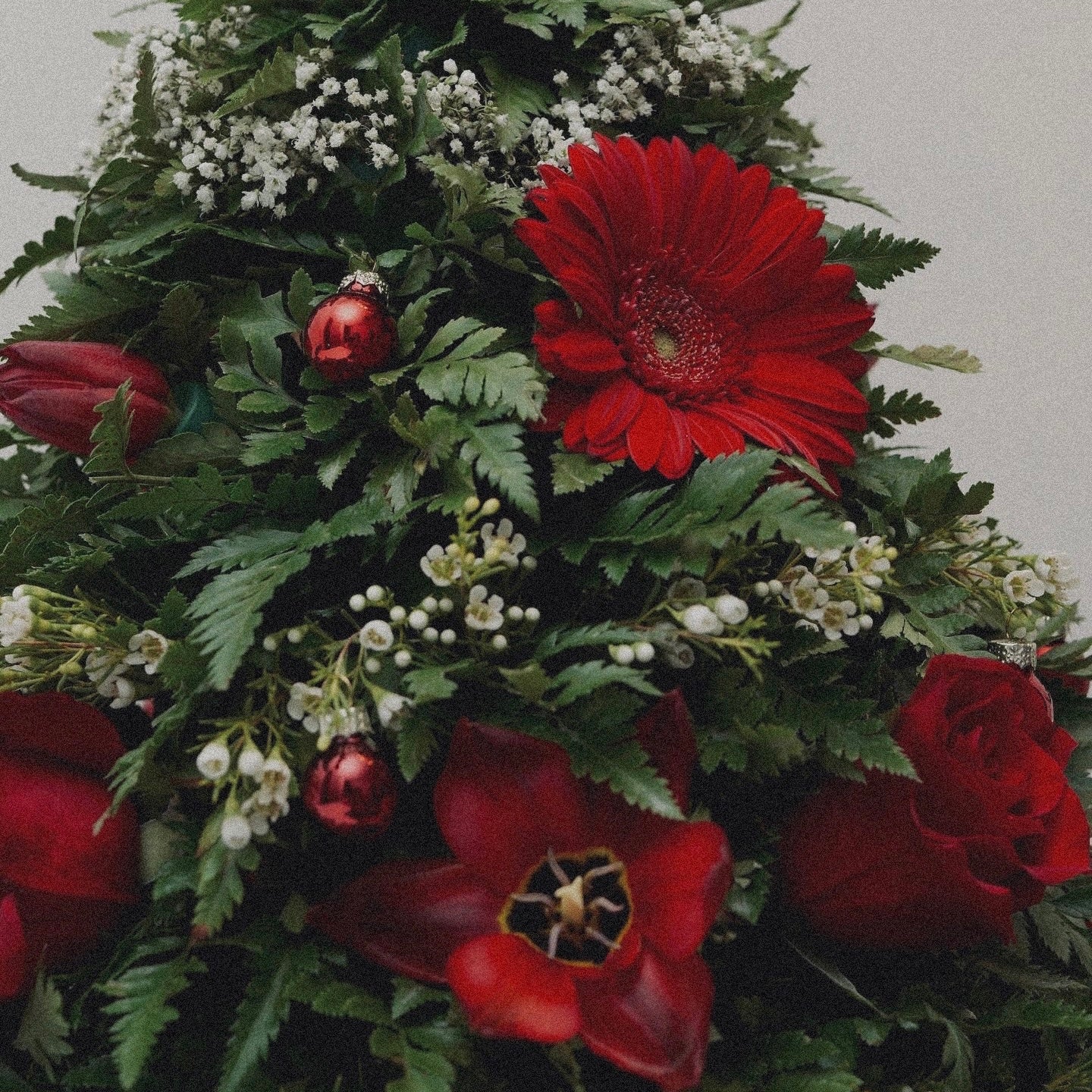 Winter-themed floral centerpiece with white roses, pinecones, and festive greenery, perfect for holiday decor.