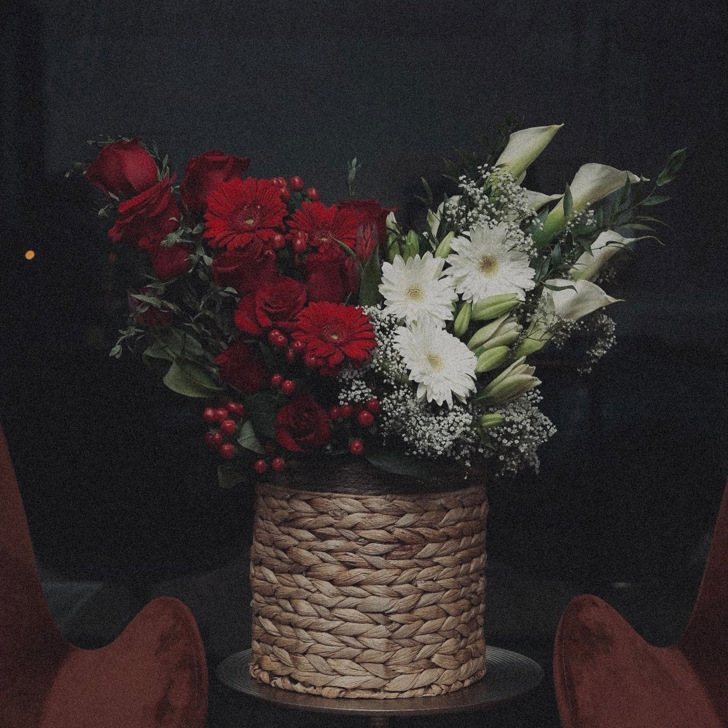 Winter-themed floral centerpiece with white roses, pinecones, and festive greenery, perfect for holiday decor.