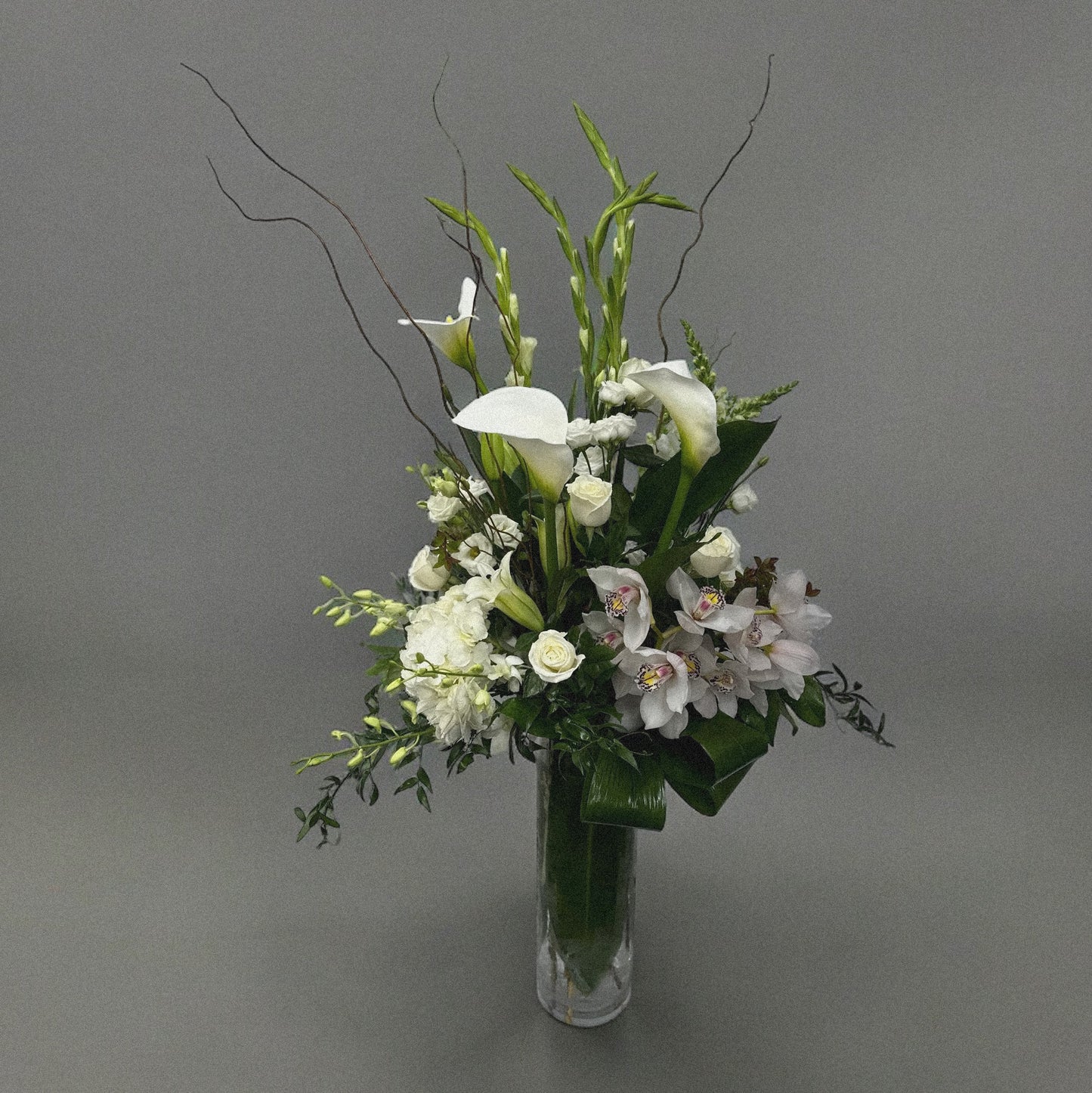 Elegant sympathy flower arrangement with white roses, lilies, and greenery, designed to express love and remembrance