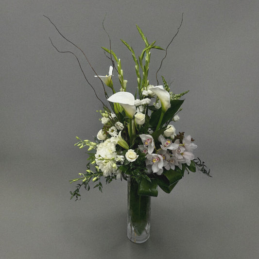 Elegant sympathy flower arrangement with white roses, lilies, and greenery, designed to express love and remembrance