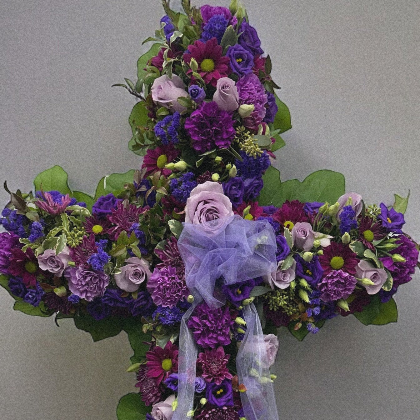 Elegant Purple Cross floral tribute with lavender flowers, symbolizing peace and spirituality, ideal for sympathy and funeral arrangements.