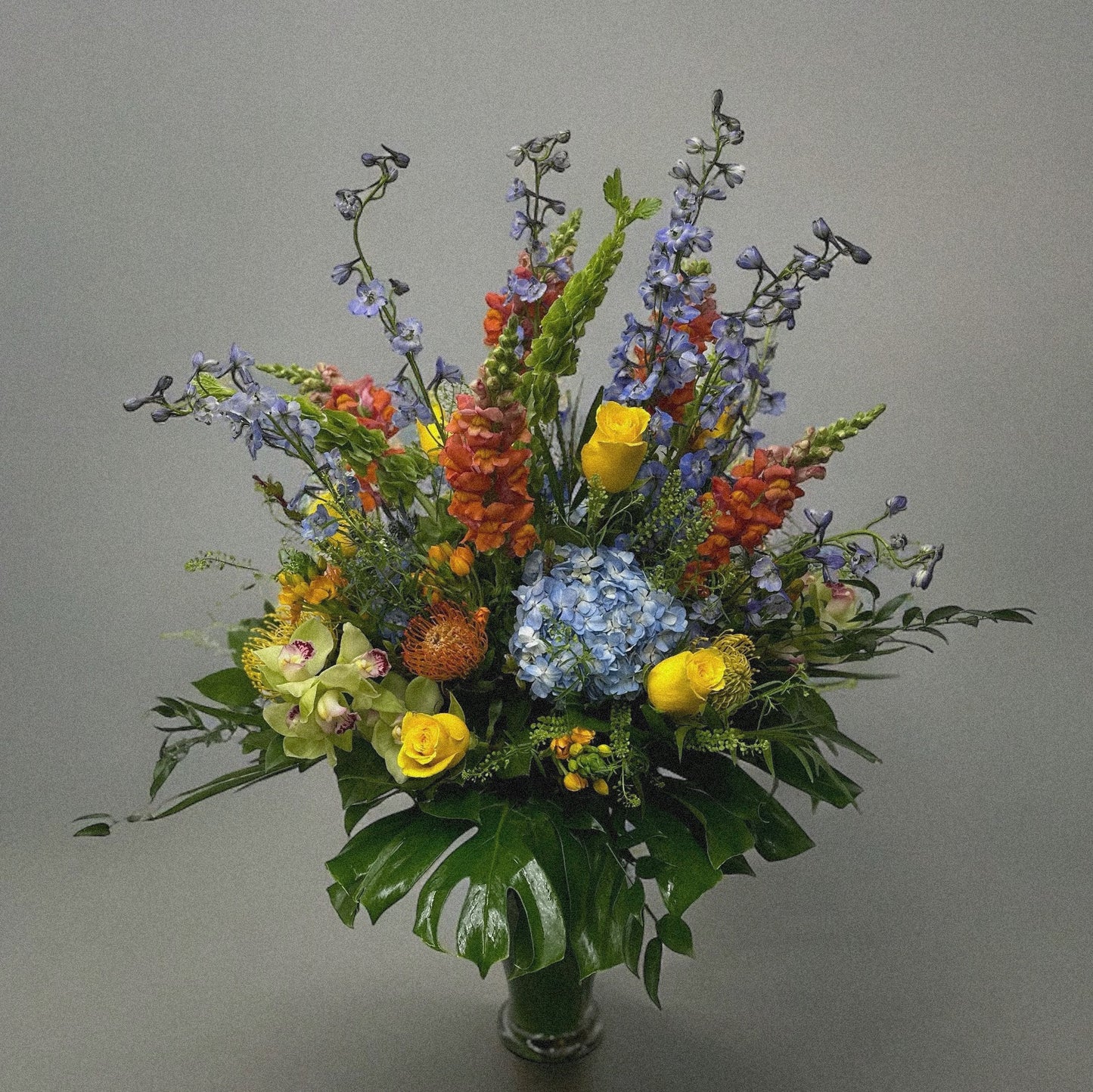 Chic and modern floral centerpiece with delicate orchids, roses, and pampas grass – perfect for sophisticated home or event decor