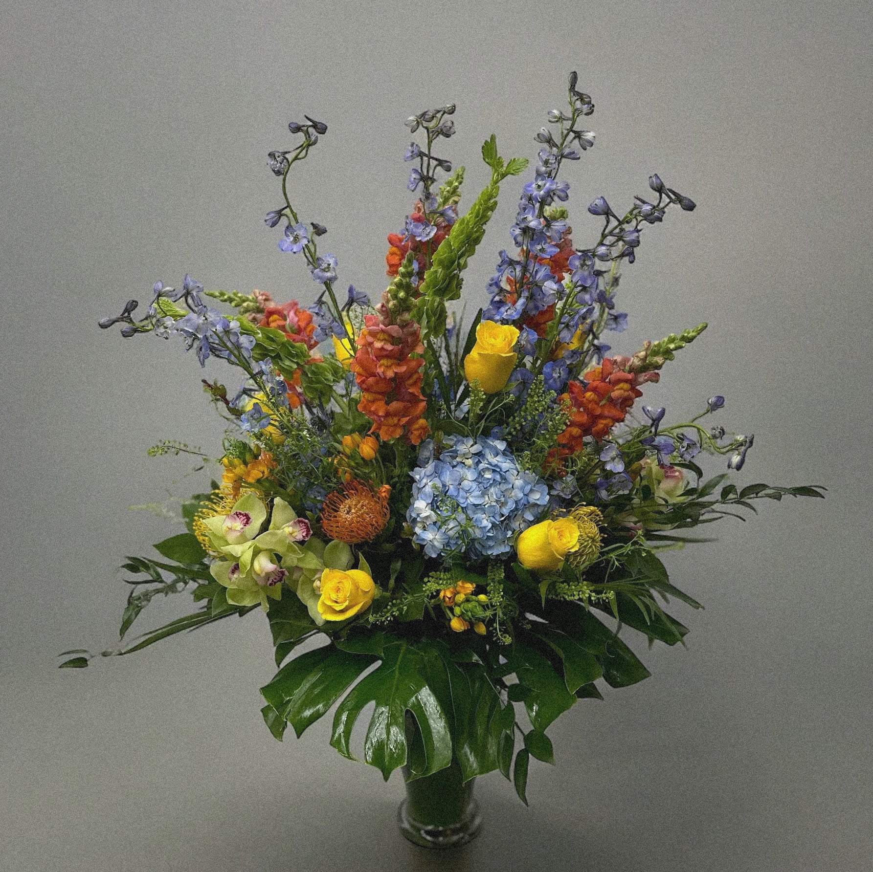 Chic and modern floral centerpiece with delicate orchids, roses, and pampas grass – perfect for sophisticated home or event decor