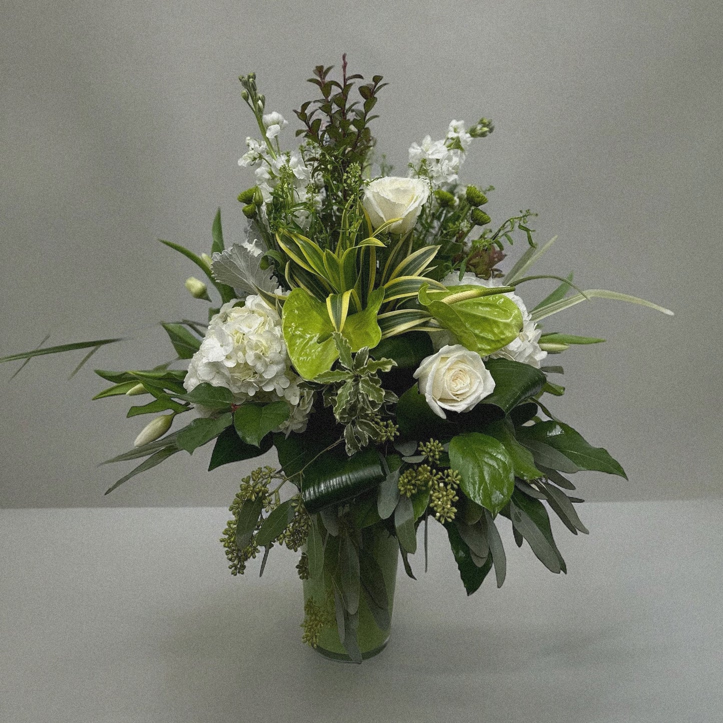 Elegant Serene Grace floral arrangement with white roses, hydrangeas, and anthuriums in a glass vase, perfect for all occasions. Best florist in Toronto, GTA.