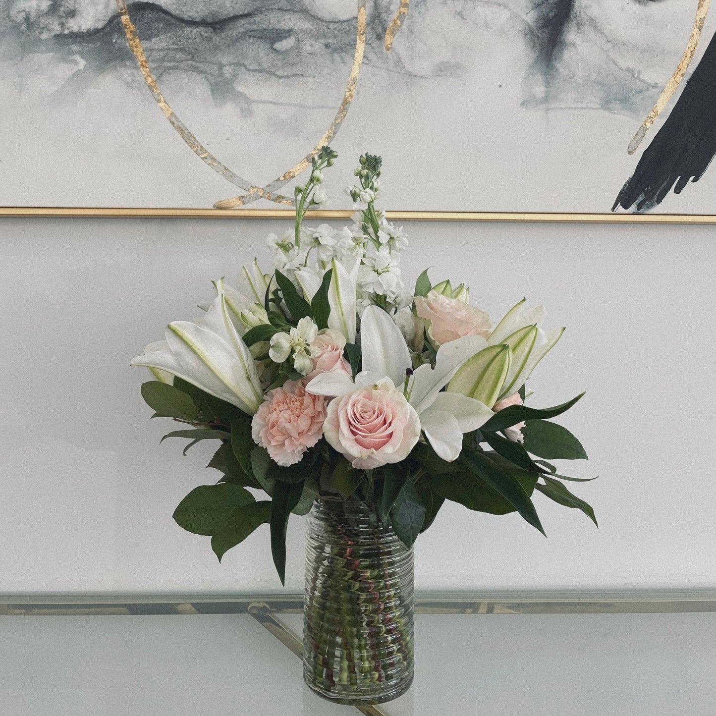 Elegant sympathy flower arrangement with white roses, lilies, and greenery, designed to express love and remembrance