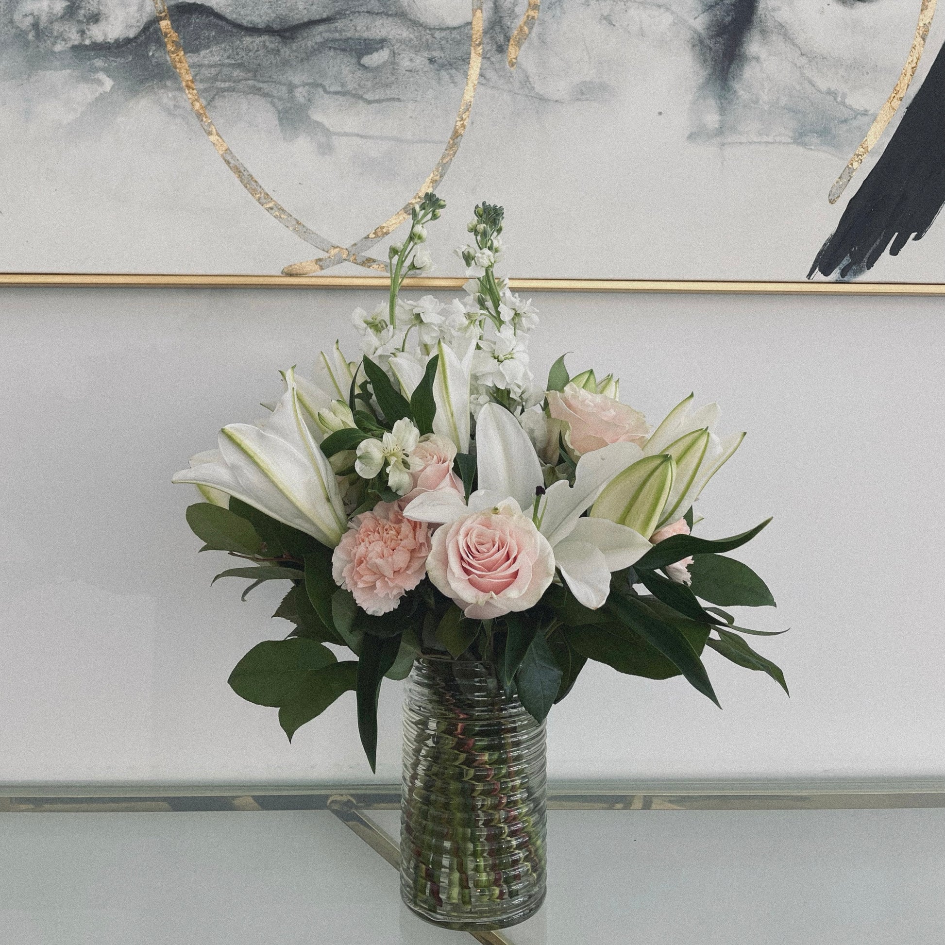 Elegant sympathy flower arrangement with white roses, lilies, and greenery, designed to express love and remembrance