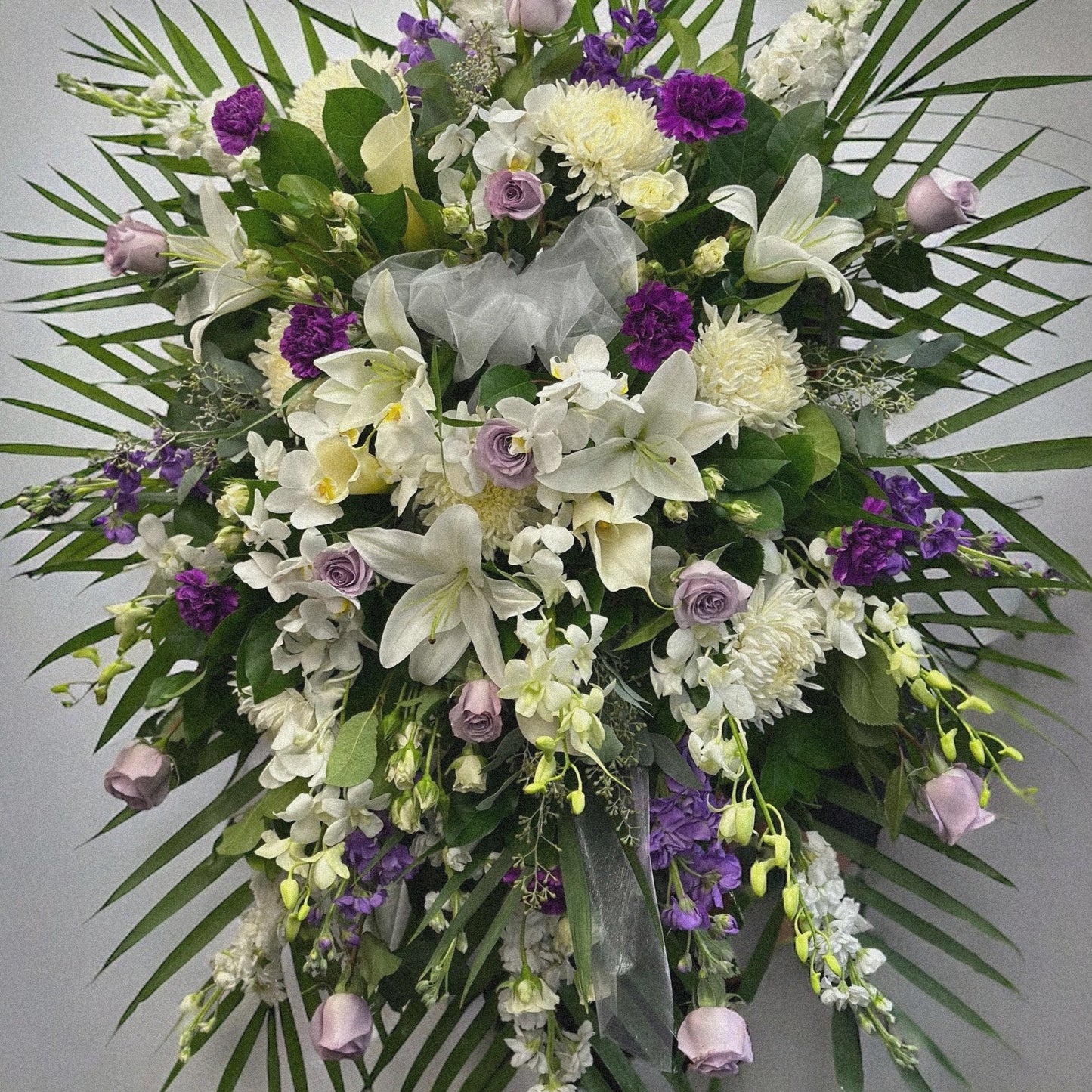 Regency Splendor standing spray with white lilies and purple blooms, a sympathy funeral wreath, available for same day delivery in Toronto.