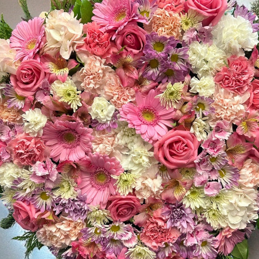 Heart-shaped wreath with soft pink and white blooms, perfect for sympathy or funeral arrangements, best luxury flowers in Toronto, same day delivery.