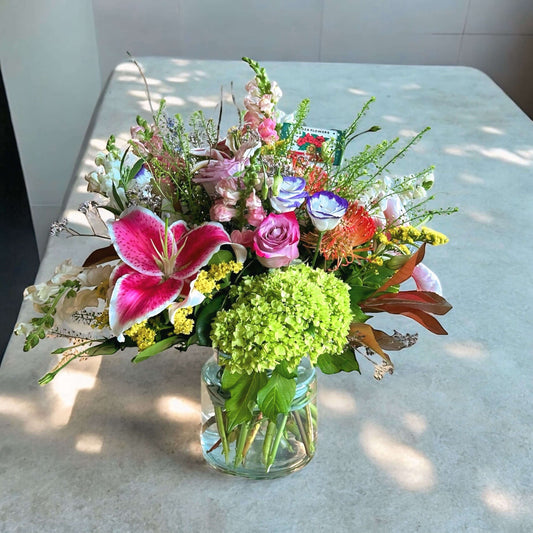 Vibrant mixed flower bouquet with bright gerbera daisies, roses, and fresh greenery, beautifully arranged for any special occasion.