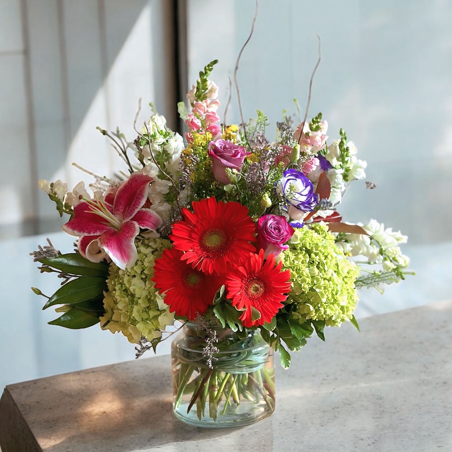 Vibrant mixed flower bouquet with bright gerbera daisies, roses, and fresh greenery, beautifully arranged for any special occasion.