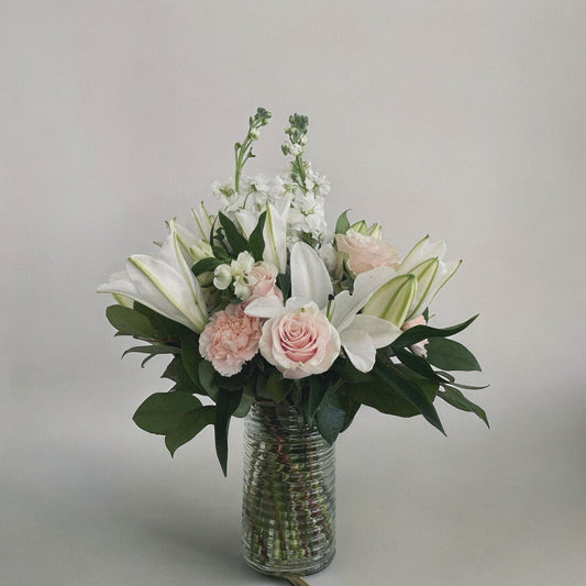 Elegant sympathy flower arrangement with white roses, lilies, and greenery, designed to express love and remembrance