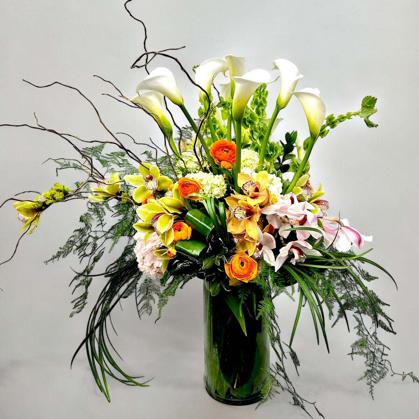 Elegant floral arrangement with white calla lilies, orange and pink blooms in a glass vase. Best Toronto florist, same day delivery.