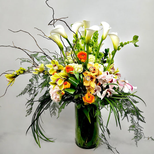 Elegant floral arrangement with white calla lilies, orange and pink blooms in a glass vase. Best Toronto florist, same day delivery.