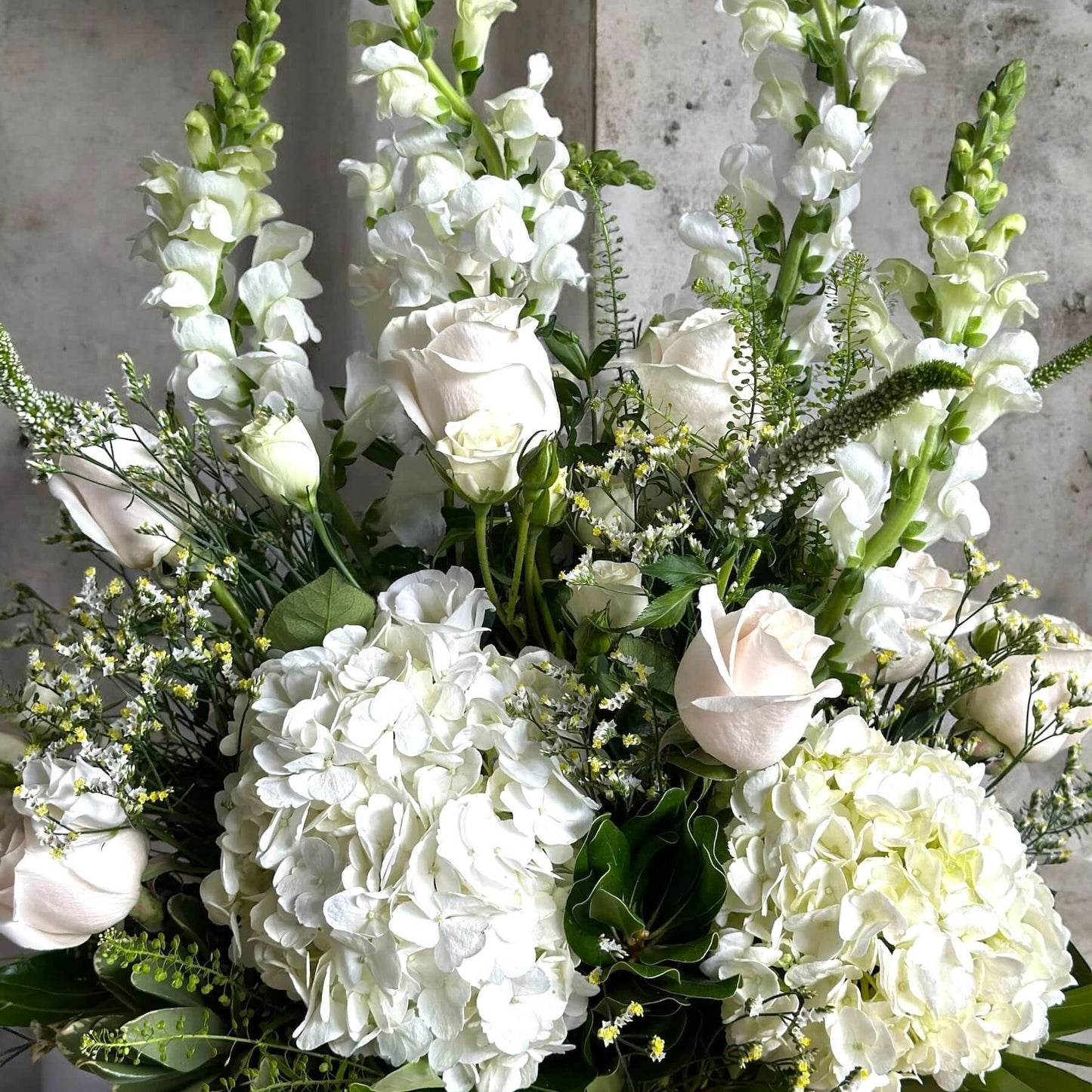 Elegant sympathy flower arrangement with white roses, lilies, and greenery, designed to express love and remembrance