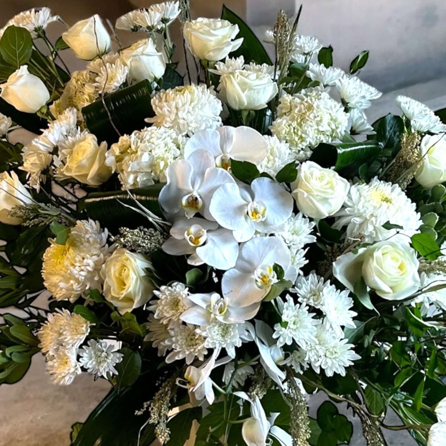 Eternal Grace Arrangement – Elegant White Sympathy & Funeral Flowers featuring roses and orchids in a graceful tribute bouquet.