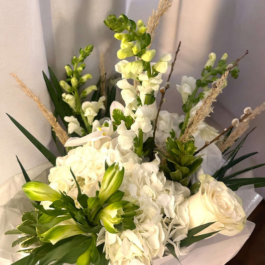 elegant sympathy flower arrangement with white roses, lilies, and greenery, designed to express love and remembrance