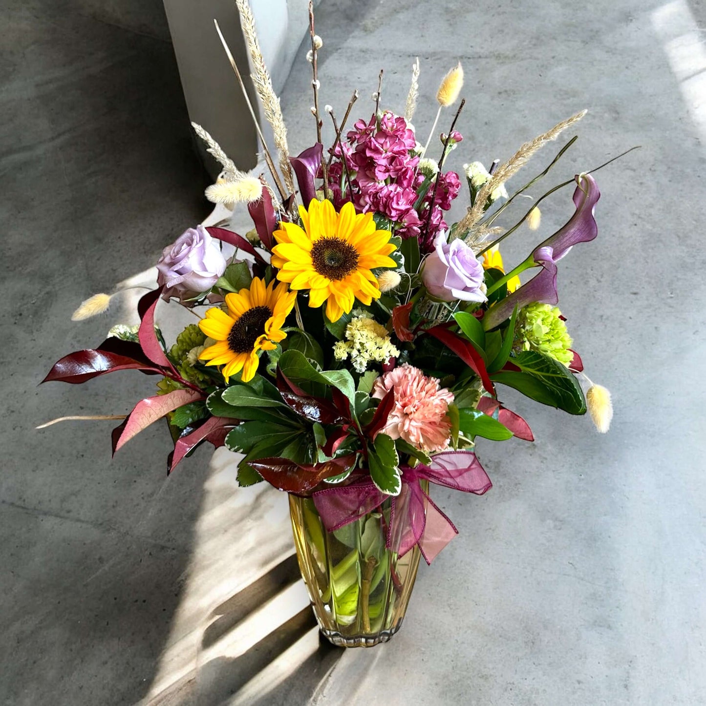 Chic and modern floral centerpiece with delicate orchids, roses, and pampas grass – perfect for sophisticated home or event decor