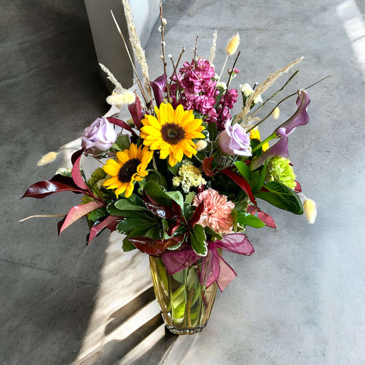 Chic and modern floral centerpiece with delicate orchids, roses, and pampas grass – perfect for sophisticated home or event decor