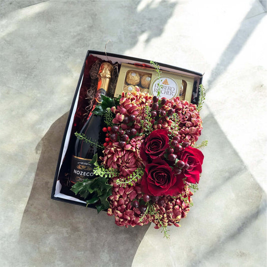 Exclusive flower and chocolate gift basket with red roses, gourmet chocolates, and fresh greenery.