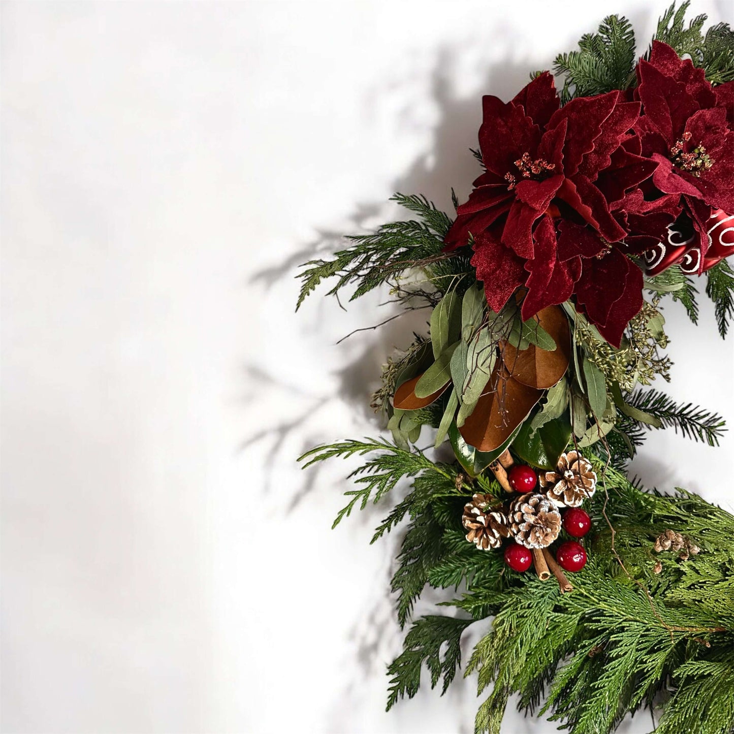 Winter-themed floral wreath with white roses, pinecones, and festive greenery, perfect for holiday decor.