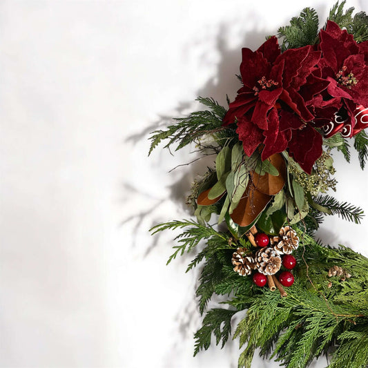 Winter-themed floral wreath with white roses, pinecones, and festive greenery, perfect for holiday decor.