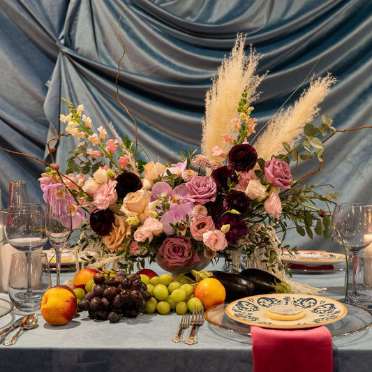 "Chic and modern floral centerpiece with delicate orchids, roses, and pampas grass – perfect for sophisticated home or event decor