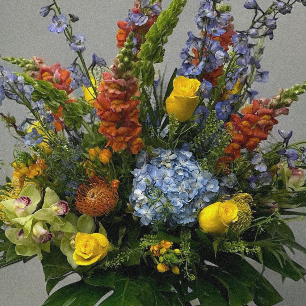 Luxury floral arrangement with vintage charm, featuring vibrant lavender delphiniums, roses, and monstera leaves. Best florist in Toronto.