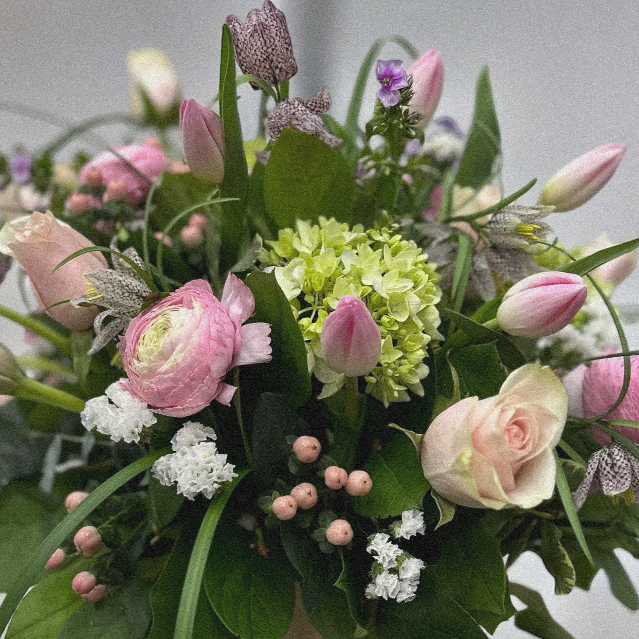 Pastel Harmony floral arrangement with pink roses, ranunculus, hydrangeas in a pink hatbox. Best florist in Toronto, luxury bouquets.
