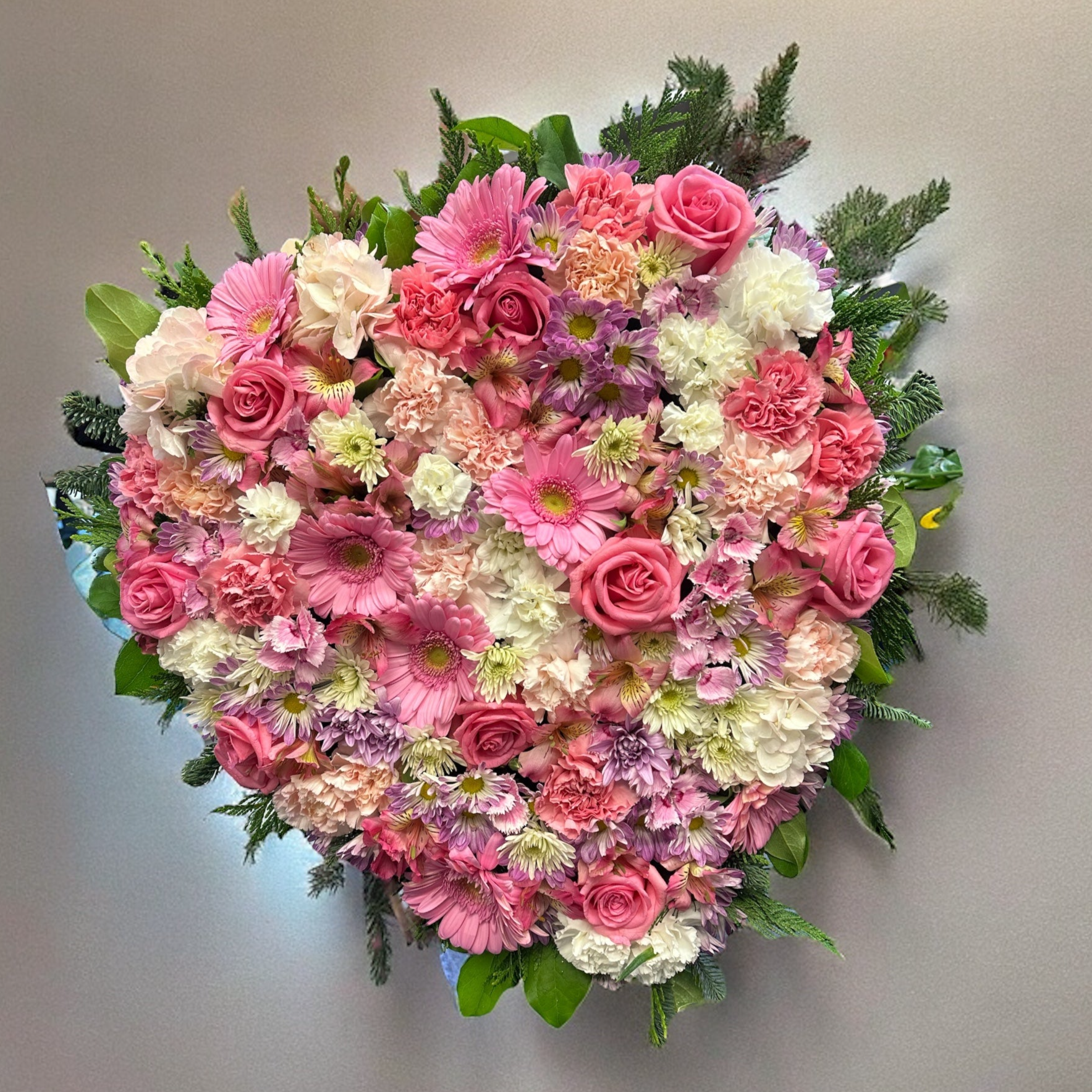 Heart-shaped floral wreath with pink roses and blooms, ideal for sympathy or funeral arrangements. Luxury same-day delivery in Toronto and GTA.