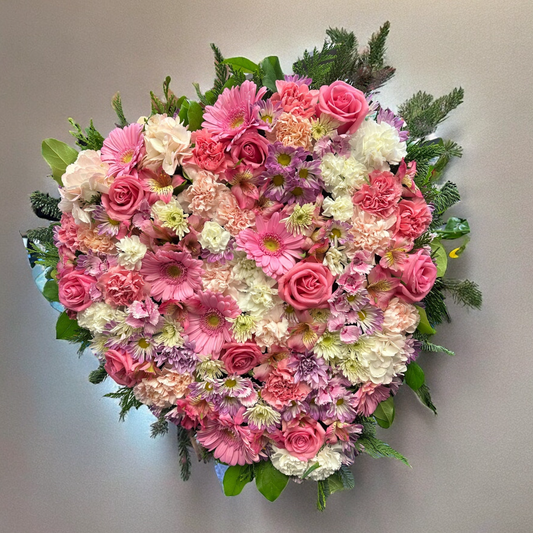 Heart-shaped floral wreath with pink roses and blooms, ideal for sympathy or funeral arrangements. Luxury same-day delivery in Toronto and GTA.