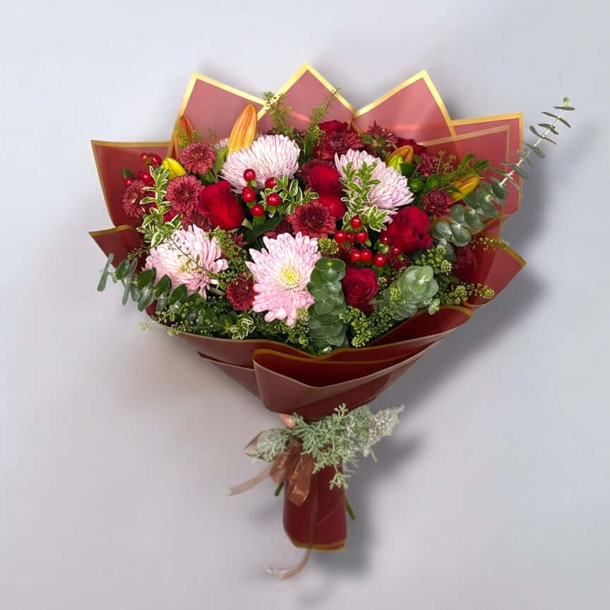 Bouquet of flowers in a decorative red holder on a light gray background